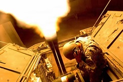 A U.S. Army Soldier holds his ears as he uses a 120mm Mortar Cannon in a Mortar Carrier Stryker vehicle to fire illumination flares.