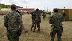 Expeditionary Medical Facility Kilo Sailors check a simulated patient for weapons during an EMF training