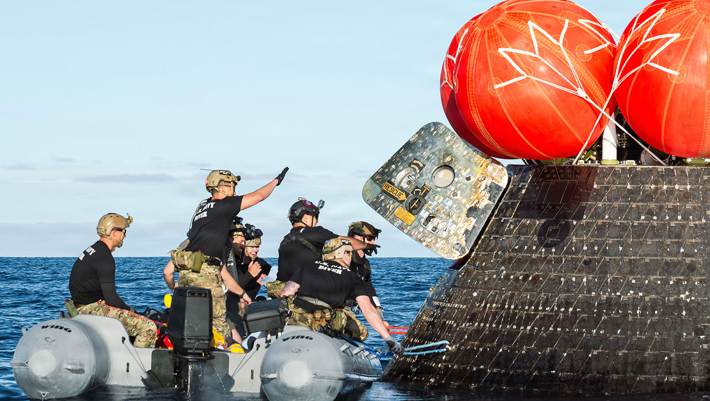 Navy divers approach NASA's Artemis II module to recover the crew in San Diego after returning from a lunar mission