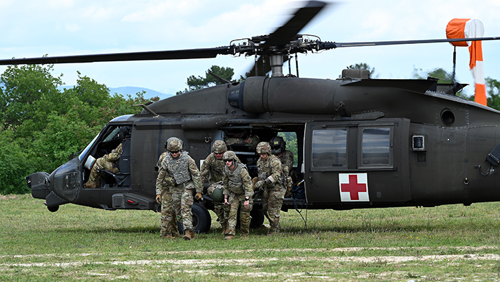Image of Military personnel exiting a helicopter.