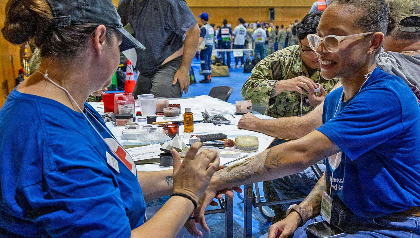 An American Red Cross Yokosuka, Japan, volunteer applies moulage to a role player during Exercise Big Rescue Kanagawa 2026