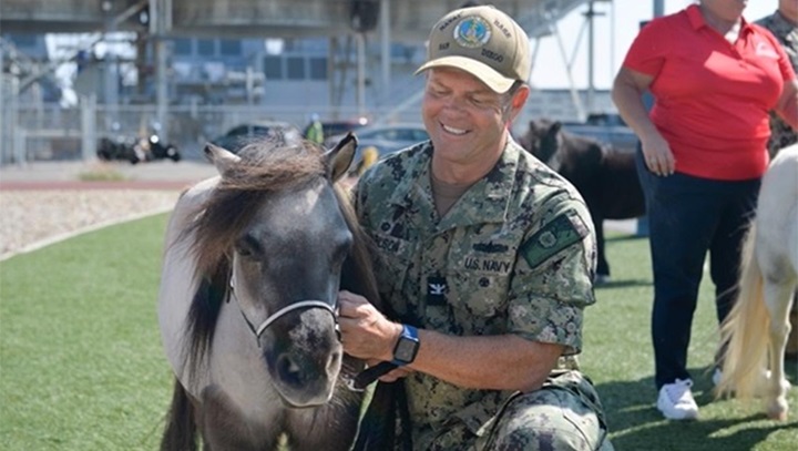 Image of Military personnel poses with miniature horse.