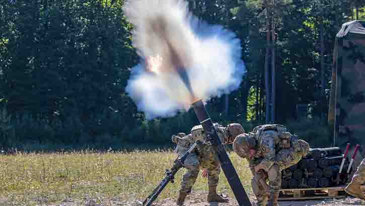 Image of Military personnel fire mortar rounds.