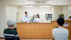 The front desk of a doctor's office with two nurses and two patients
