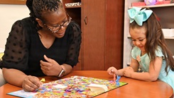 Maxine “Angela” Kuesters, a psychology technician with Bayne-Jones Army Community Hospital, plays a board game with Rosemary Pando, daughter of Reyna Pando and Air Force Sgt. Christopher Pando