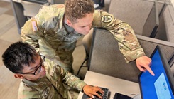 Two services members working at the computer