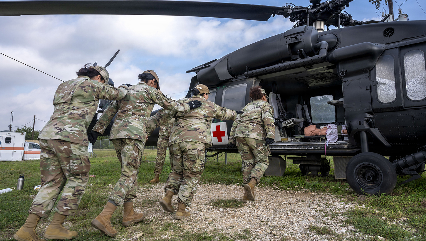 U.S. Air Force students practicing how to safely approach a HH60M Black Hawk medical evacuation helicopter frame