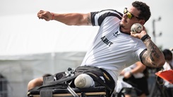 Military personnel in a wheel chair throwing a shot put ball