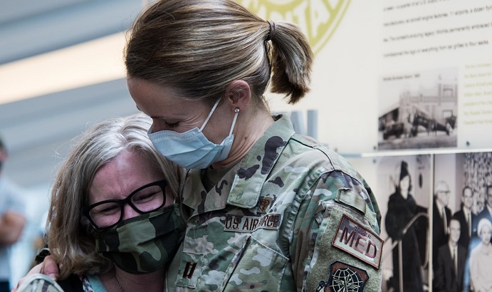 Image of Military health personnel wearing face masks hugging. Click to open a larger version of the image.