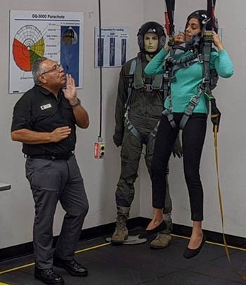 Military personnel testing an ejection seat parachute harness