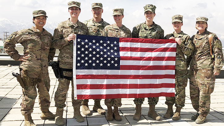 Seven soldiers standing behind an American flag