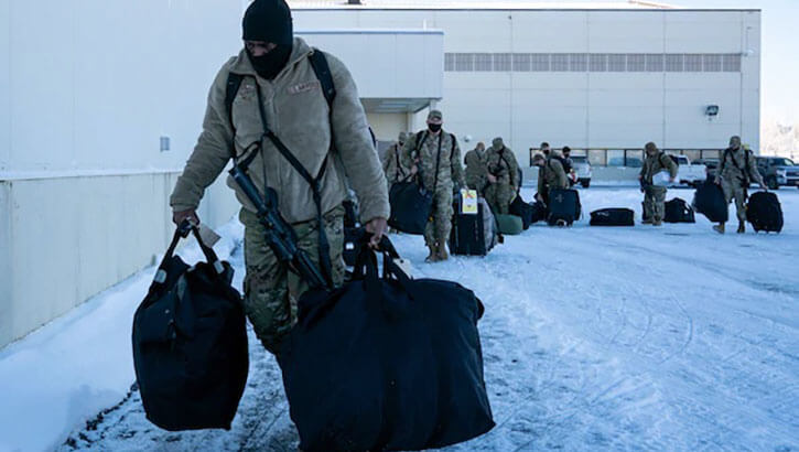 Airman in winter gear carry deployment gear at Joint Base Elmendorf Richardson, Alaska in preparation for Operation Polar Force exercise