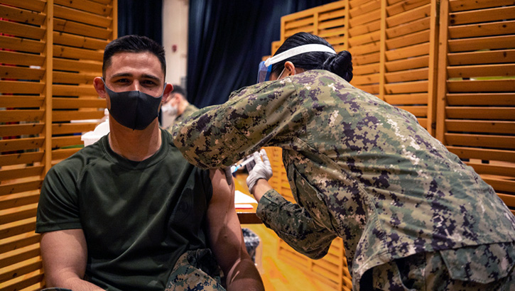 Image of Soldier getting a vaccine in his left arm.