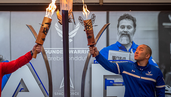 Image of U.S. Air Force Senior Master Sgt. Aaron Lin, right, and a wounded warrior from the U.S. Marine Corps light the Wounded Warrior Trials cauldron during the opening ceremony at Joint Base San Antonio – Randolph, March 14, 2025. Lin shares his story of recovering from posttraumatic stress disorder through the help of leadership, his family, and the care of the Military Health System.