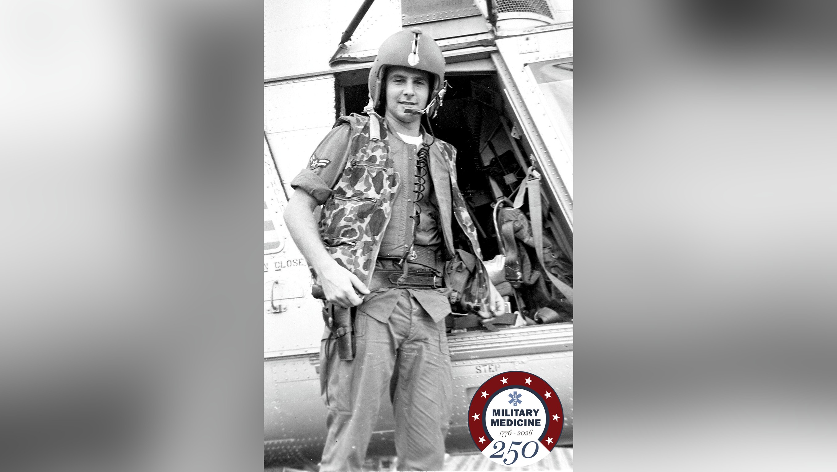 U.S. Air Force A1C William H. Pitsenbarger stands ready for a rescue mission next to a helicopter.