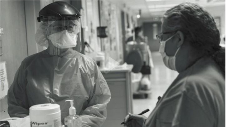 Black and white image of two nurses wearing PPE in a hospital setting